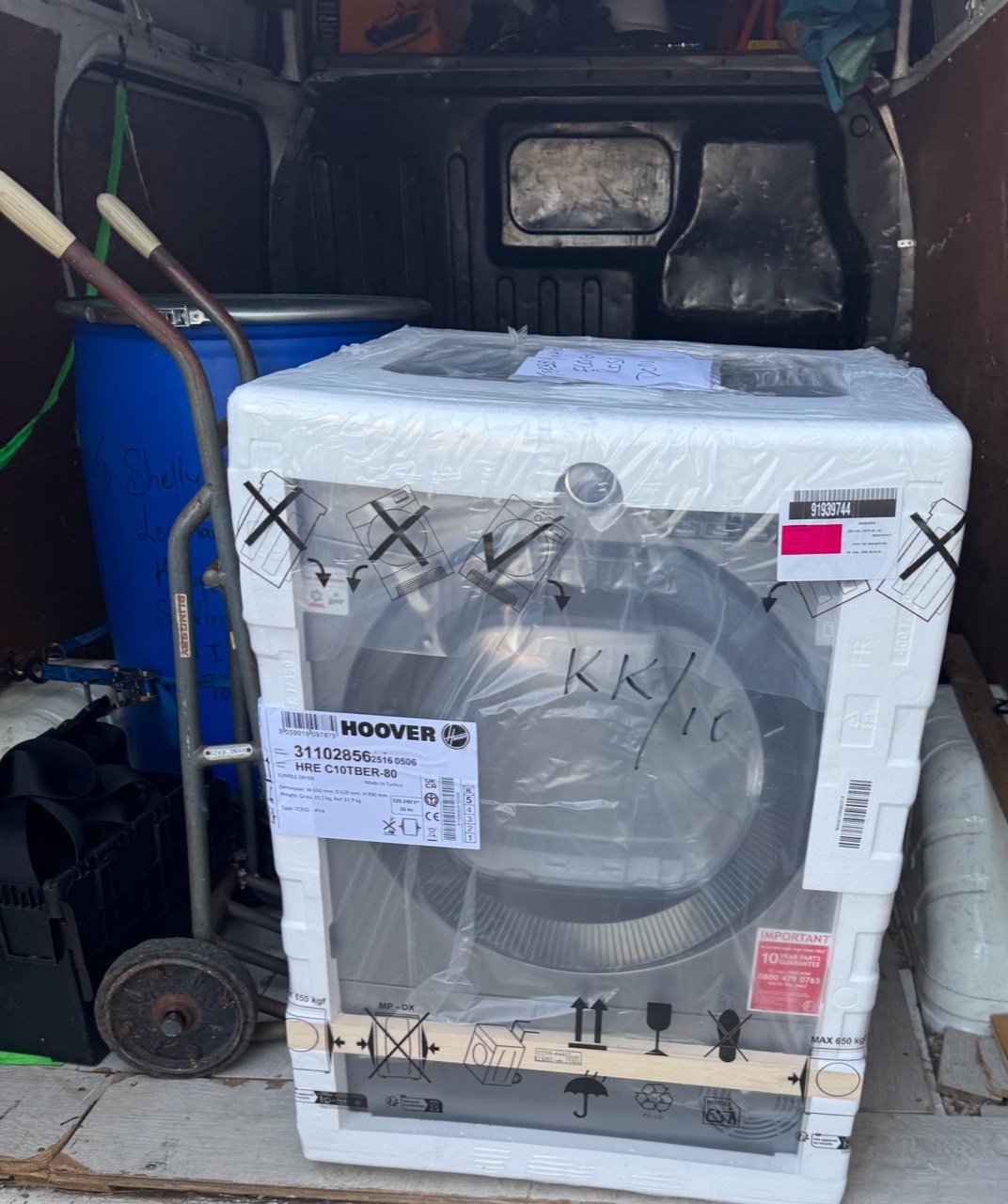 New tumble dryer secured upright inside the van with a sack truck beside it