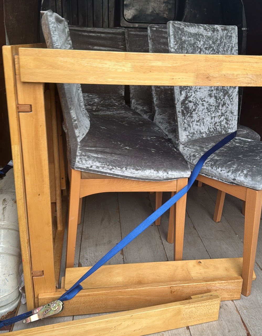 Wooden dining table and grey chairs secured in the van